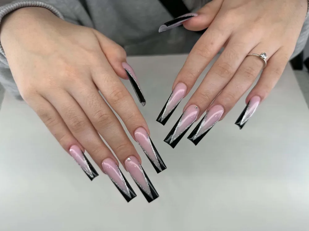 Extra-long coffin nails in soft pink with glossy black tips and a fine silver glitter chevron