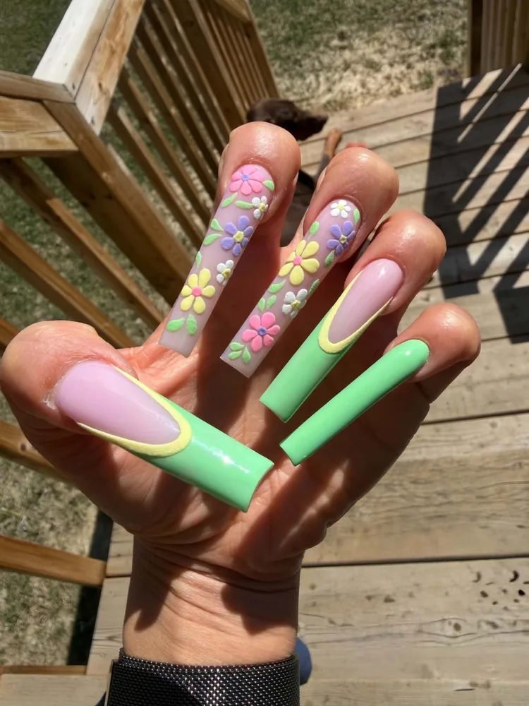 Extra-long square nails with mint green tips outlined in yellow, and clear accent nails covered in pastel 3D daisies