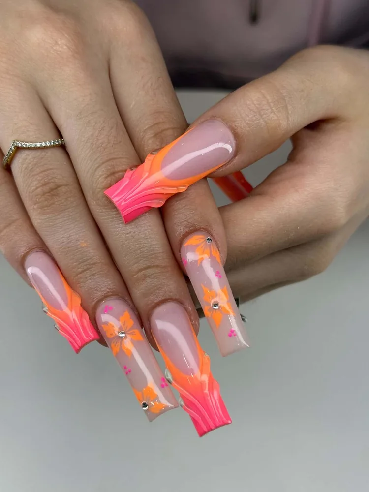 Long square nails with neon orange and pink swirled tips and hand-painted hibiscus flowers set with crystals