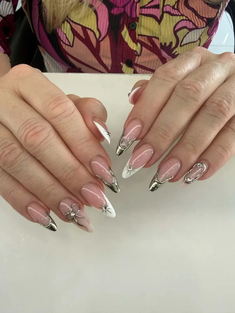 Almond nails in nude pink with raised silver chrome accents, white tips and silver starburst detailing