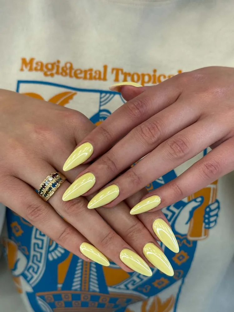 Long almond nails in a solid butter yellow with a high-gloss finish