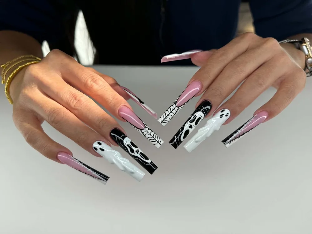 Long square Halloween nails in black, white and pink with painted ghost faces, spiderwebs and stitch detailing